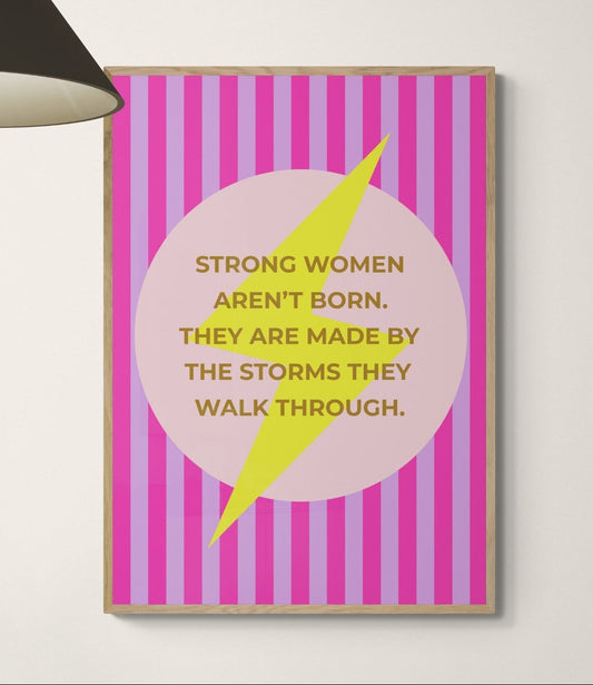Motivational poster on a wall above a desk with office furniture saying Strong women aren't born. They are made by the storms they walk through on top of a lightening bolt.