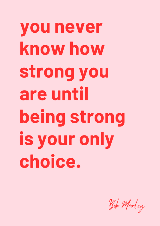 A framed art print with a pink background and red text featuring the quote 'You never know how strong you are until being strong is your only choice.' by Bob Marley, displayed on a wall above a wooden bench with a striped cushion.