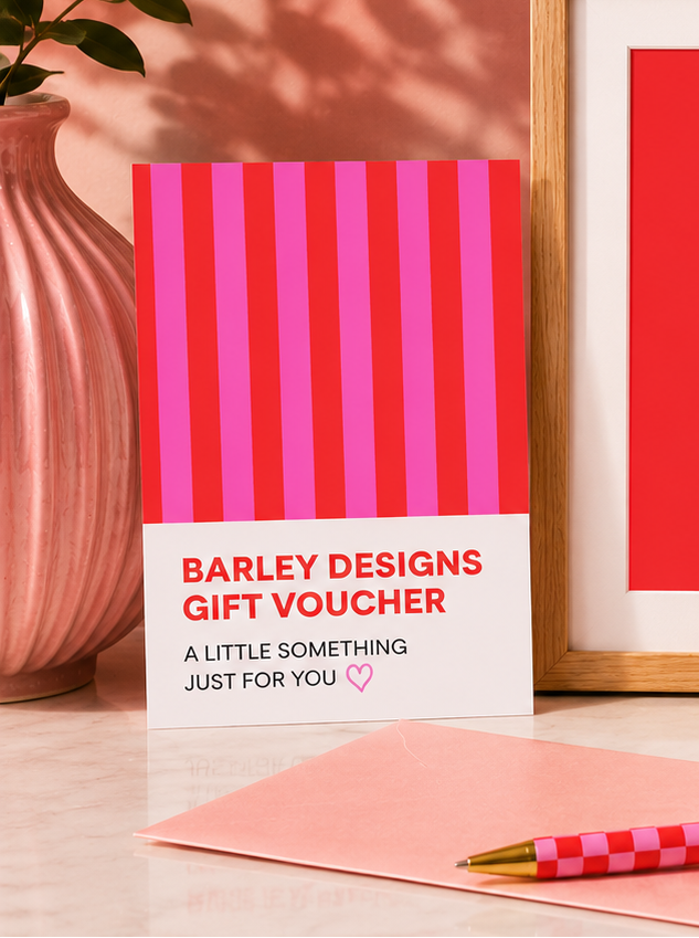 Barley deisgns gift voucher, pen, and ribbons on a wooden surface.