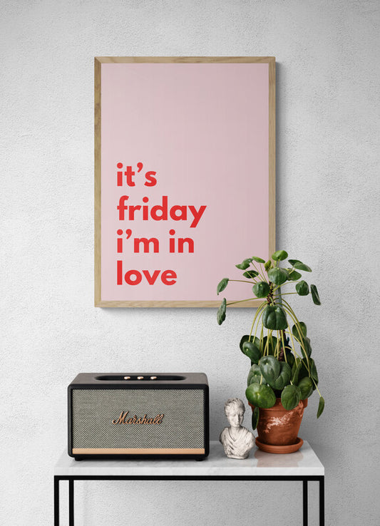 Framed poster with 'it's friday i'm in love' text, Marshall speaker, plant, and bust on a table against a gray wall.