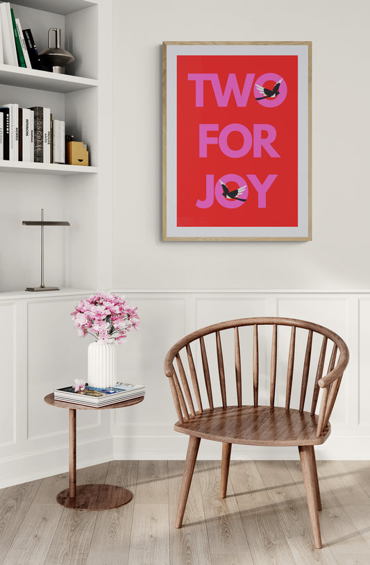 Wooden chair in a room with a 'Two for Joy' poster on the wall with two magpies highlighting two birds bringing joy. 